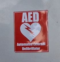 Load image into Gallery viewer, AED sticker on a wall with a red background and white text.