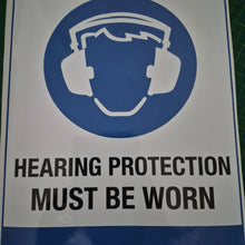Load image into Gallery viewer, Sign with a hard hat icon and text 'Hearing protection must be worn' on a blue and white background.