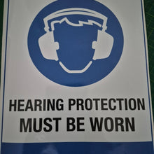 Load image into Gallery viewer, Sign with a hard hat icon and text 'Hearing protection must be worn' on a blue and white background.