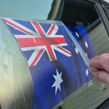 Load image into Gallery viewer, Person applying an Australian flag decal to a car window