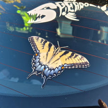 Load image into Gallery viewer, Butterfly-shaped decal on a car window with a skeleton and plant design in the background.
