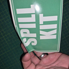 Load image into Gallery viewer, Hand holding a green sign with 'SPILL KIT' text on a cutting mat background