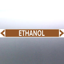 Load image into Gallery viewer, A pipe marker label with the word 'ETHANOL' in bold black lettering on a golden tan background with a white border and green directional arrows pointing in both directions.