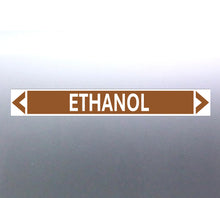 Load image into Gallery viewer, A pipe marker label with the word 'ETHANOL' in bold black lettering on a golden tan background with a white border and green directional arrows pointing in both directions.