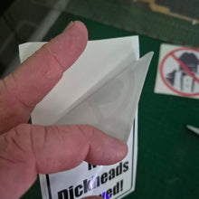 Load image into Gallery viewer, Hand holding a small white object with a green surface and 'Dickhead' sticker in the background