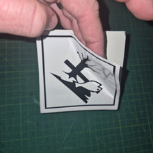 Load image into Gallery viewer, Hand holding a small black and white sticker with a design on a green cutting mat.