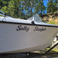 Load image into Gallery viewer, White boat named 'Salty Starfish' on a trailer with trees in the background