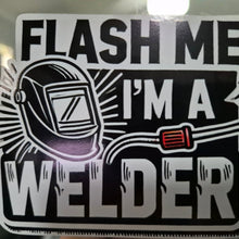 Load image into Gallery viewer, Sticker with a welding helmet and text 'Flash me I'm a welder' on a reflective surface.