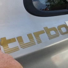 Load image into Gallery viewer, Gold 'turbo' decal being applied to a car door