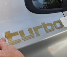 Load image into Gallery viewer, Gold 'turbo' decal being applied to a car door