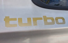 Load image into Gallery viewer, Gold 'turbo' decal on a car's white surface