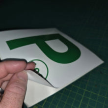 Load image into Gallery viewer, Hand holding a small white object with a green logo on a dark background