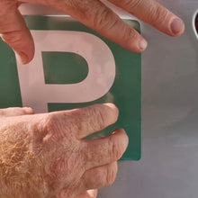 Load image into Gallery viewer, Hand placing a green license plate with a white 'P' on a vehicle.