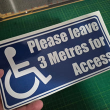Load image into Gallery viewer, Handheld sign with wheelchair icon and text 'Please leave 3 Metres for Access' on a green cutting mat.