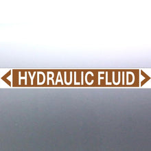 Load image into Gallery viewer, A rectangular brown label with the text 'HYDRAULIC FLUID' in bold white letters, surrounded by a white border and green arrows at the ends.