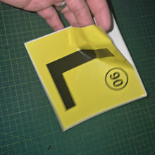 Load image into Gallery viewer, Yellow square with a black 'L' shape and number 90 on a green cutting mat.