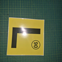 Load image into Gallery viewer, Yellow square with black 'L' and black circle with number 90 on a green grid background