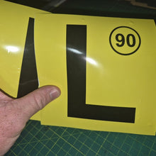 Load image into Gallery viewer, Yellow sign with a black 'L' and number 90 held by a hand on a green cutting mat.
