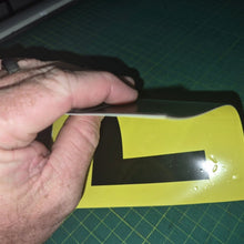 Load image into Gallery viewer, Hand holding a black 'L' plate on a yellow background with a green cutting mat.