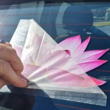 Load image into Gallery viewer, Hand holding a pink flower-shaped car decal against a car window.