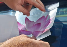 Load image into Gallery viewer, Person peeling back a car window film with a pink flower design.