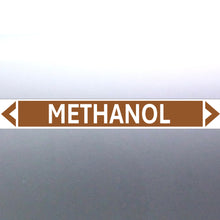 Load image into Gallery viewer, A pipe marker label with the word 'METHANOL' in bold black lettering on a golden tan background, with a white border and green directional arrows pointing in both directions.
