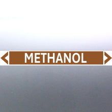 Load image into Gallery viewer, A pipe marker label with the word 'METHANOL' in bold black lettering on a golden tan background, with a white border and green directional arrows pointing in both directions.