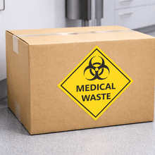 Load image into Gallery viewer, Cardboard box with a biohazard medical waste label in an indoor setting.