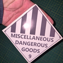 Load image into Gallery viewer, Sticker with 'Miscellaneous Dangerous Goods' text held over a green cutting mat.