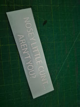 Load image into Gallery viewer, Rectangular decal with offensive text on a green cutting mat