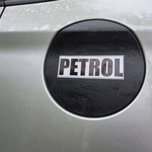 Load image into Gallery viewer, A close-up of a silver car fuel door with a black circular emblem featuring the word 'PETROL' in white letters.