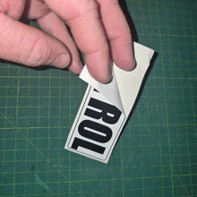 Load image into Gallery viewer, Hand holding a sticker with 'PETROL' decal on a green cutting mat.