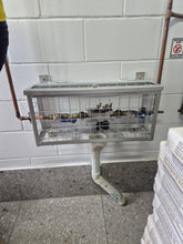 Load image into Gallery viewer, Plumbers cage attached to a wall with pipes and a stack of newspapers on the ground.