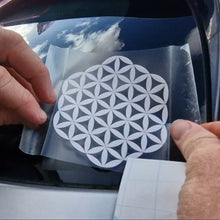 Load image into Gallery viewer, Person applying a white flower of life decal to a car window, geometric design sticker