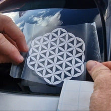 Load image into Gallery viewer, Person applying a white flower of life decal to a car window, geometric design sticker