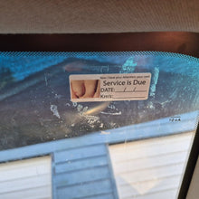 Load image into Gallery viewer, Car windshield with a service due reminder sticker on a blurred background