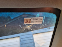 Load image into Gallery viewer, Car windshield with a service due reminder sticker on a blurred background
