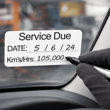 Load image into Gallery viewer, Hand writing on a car window with a service due date label.