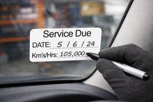 Load image into Gallery viewer, Hand writing on a car window with a service due date label.