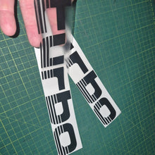 Load image into Gallery viewer, Two 'Turbo' decals held over a green cutting mat.