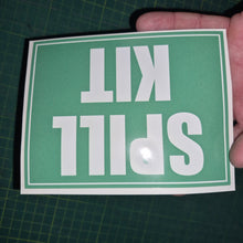 Load image into Gallery viewer, Hand holding a green sign with 'SPILL KIT' text on a grid background