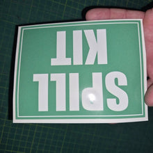 Load image into Gallery viewer, Hand holding a green sign with 'SPILL KIT' text on a grid background
