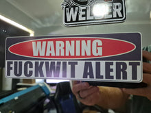 Load image into Gallery viewer, Sticker with 'WARNING FUCKWIT ALERT' text held by a person, with a blurred background.