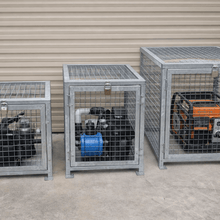 Load image into Gallery viewer, Three metal cages with generators inside against a wall.