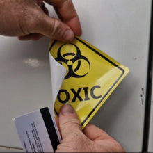 Load image into Gallery viewer, Person affixing a biohazard sign to a surface