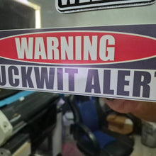 Load image into Gallery viewer, Warning sticker with text 'WARNING FUCKWIT ALERT' held in front of a machine.