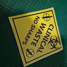 Load image into Gallery viewer, Yellow warning label with 'Clinical Waste No Sharps' text on a green cutting mat.