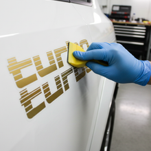 Load image into Gallery viewer, Applying gold Turbo sticker with squeegee