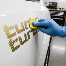 Load image into Gallery viewer, Applying gold Turbo sticker with squeegee