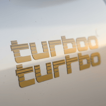 Load image into Gallery viewer, Close-up gold Turbo sticker on 4WD panel